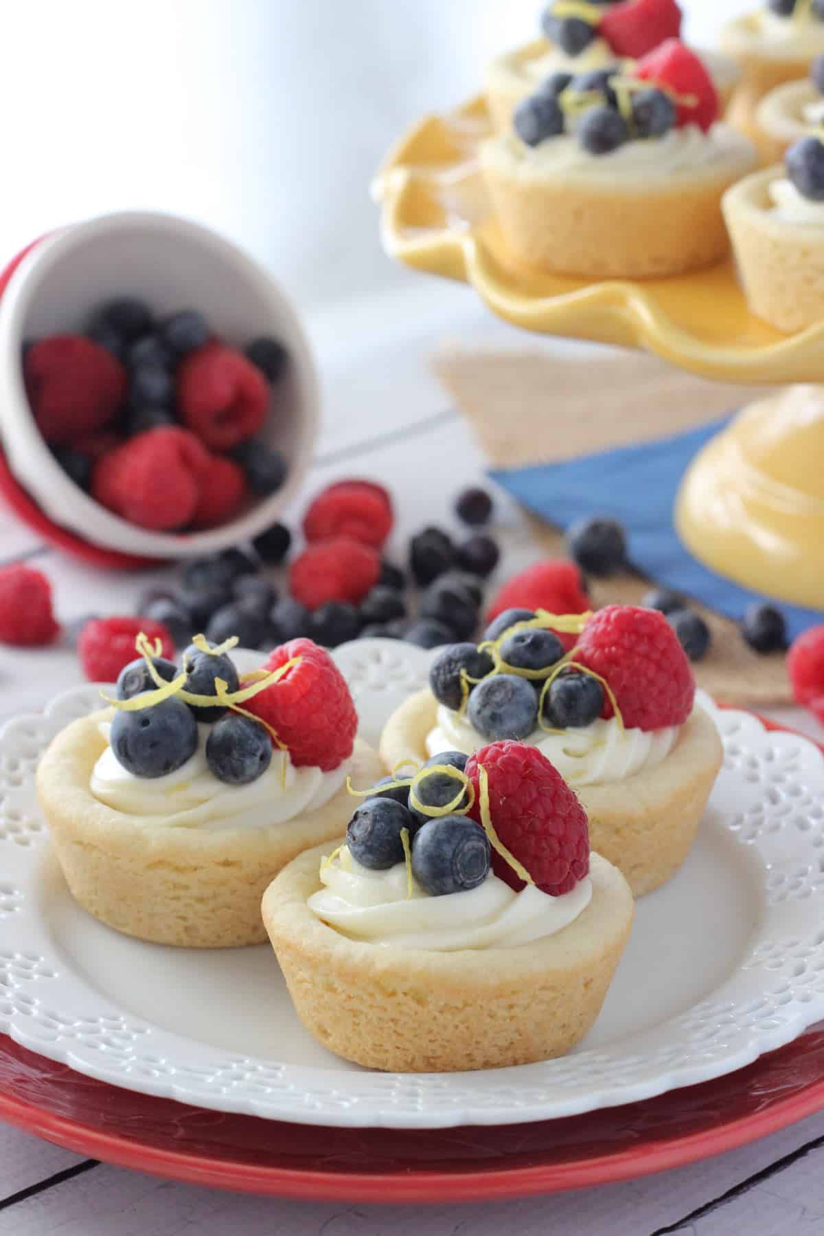 Three berry lemon cheesecake cookie cups on a small white plate.