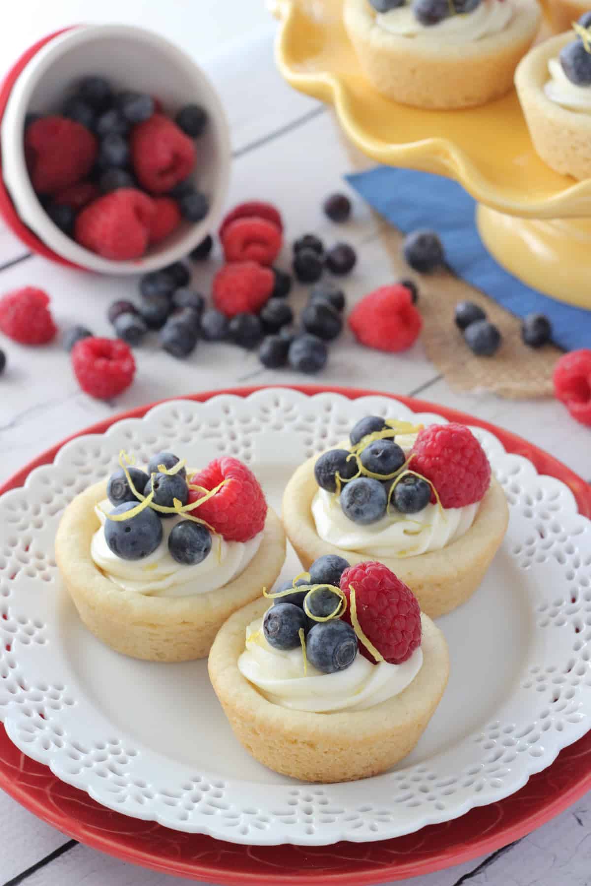 Three berry lemon cheesecake cookie cups on a small white plate.