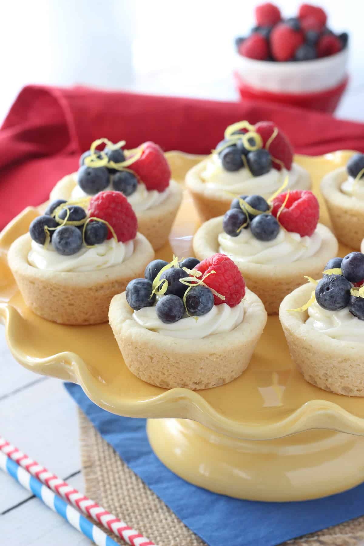 Berry lemon cheesecake cookie cups on a yellow cake stand.
