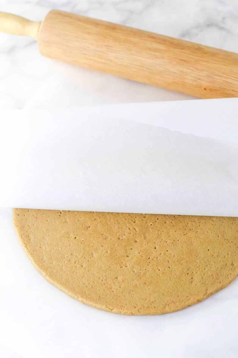 These brown sugar cutout cookies are the best! Browning the butter gives them a nutty, caramelized flavor and a dreamy, soft, chewy texture. Brown butter cookie dough rolled out between two sheets of parchment paper.