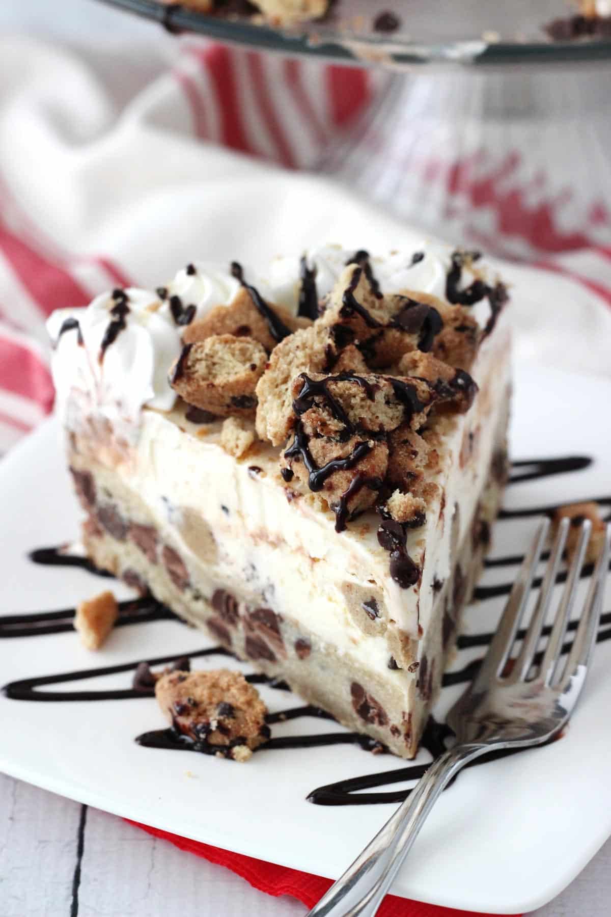 A slice of chocolate chip cookie ice cream cake on a white plate.