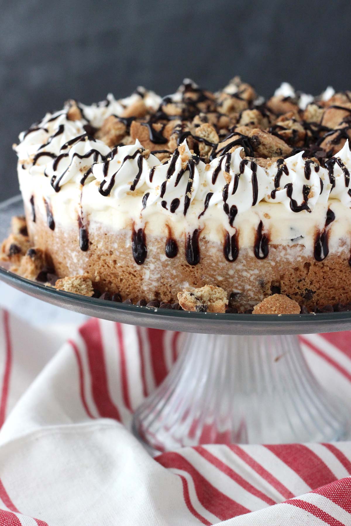 Side view of a chocolate chip cookie ice cream cake on a cake plate.