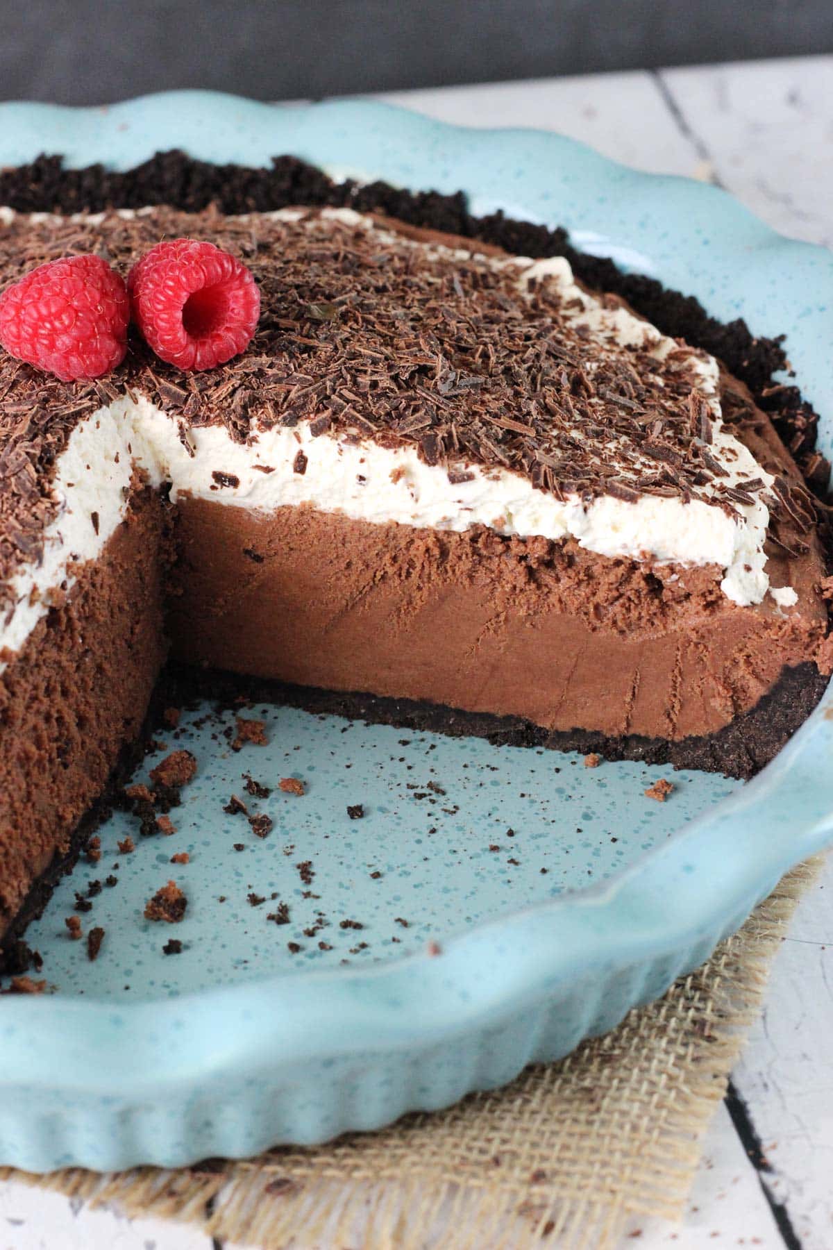 A chocolate truffle pie in a blue ceramic pie plate with slices removed to show layers.