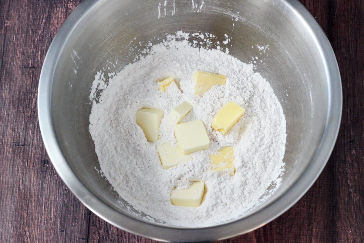 Chunks of butter in a bowl is biscuit ingredients.