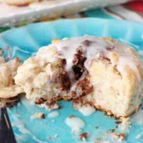 A biscuit on a blue plate with several bites removed.