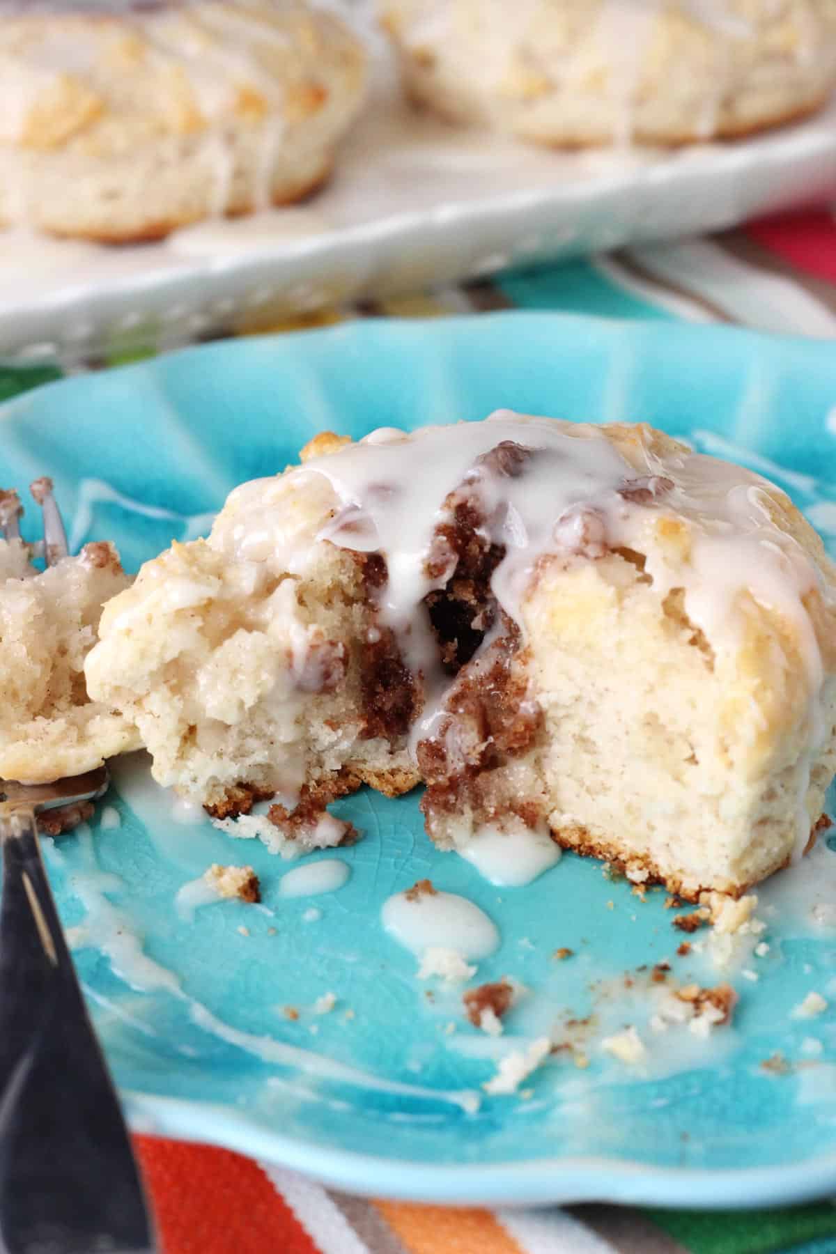 A biscuit on a blue plate with several bites removed.