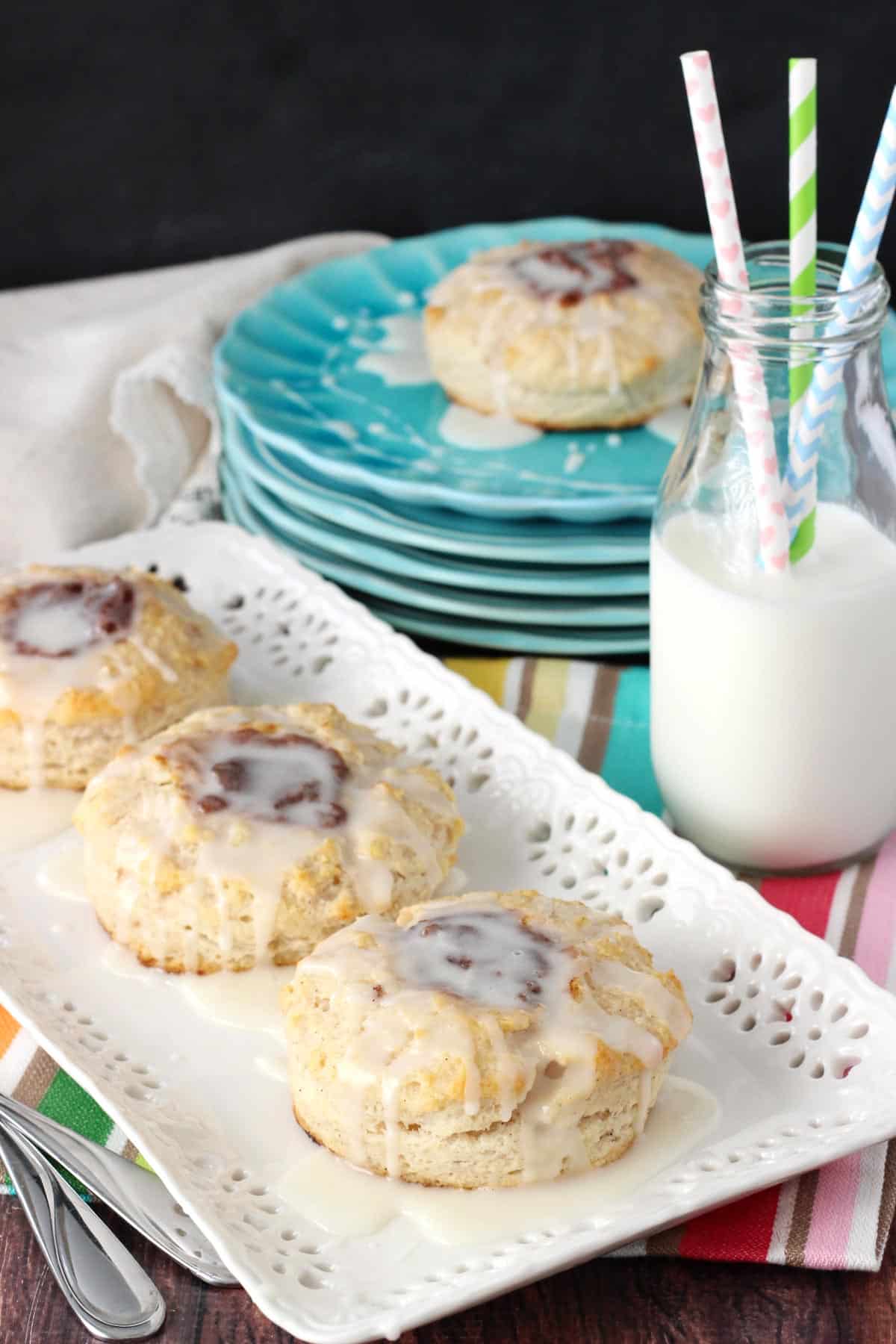 Three biscuits on a white tray next to milk.