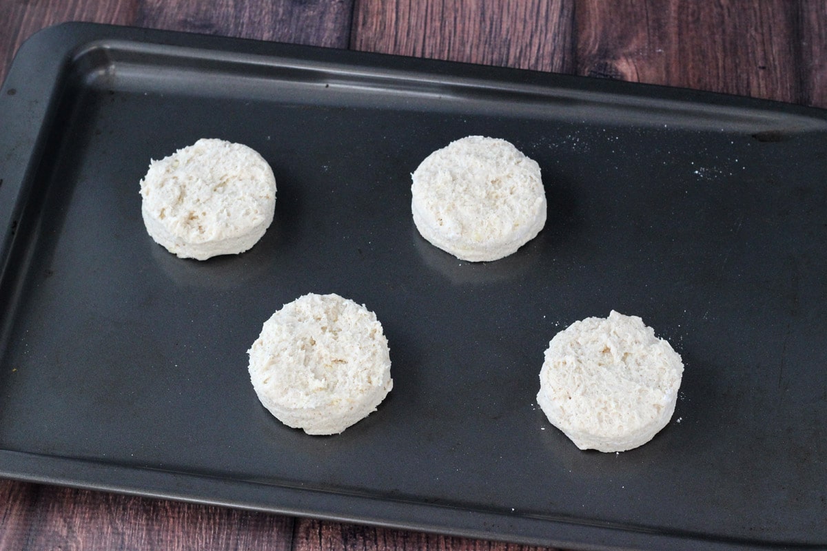 Four dough biscuits on a baking tray.