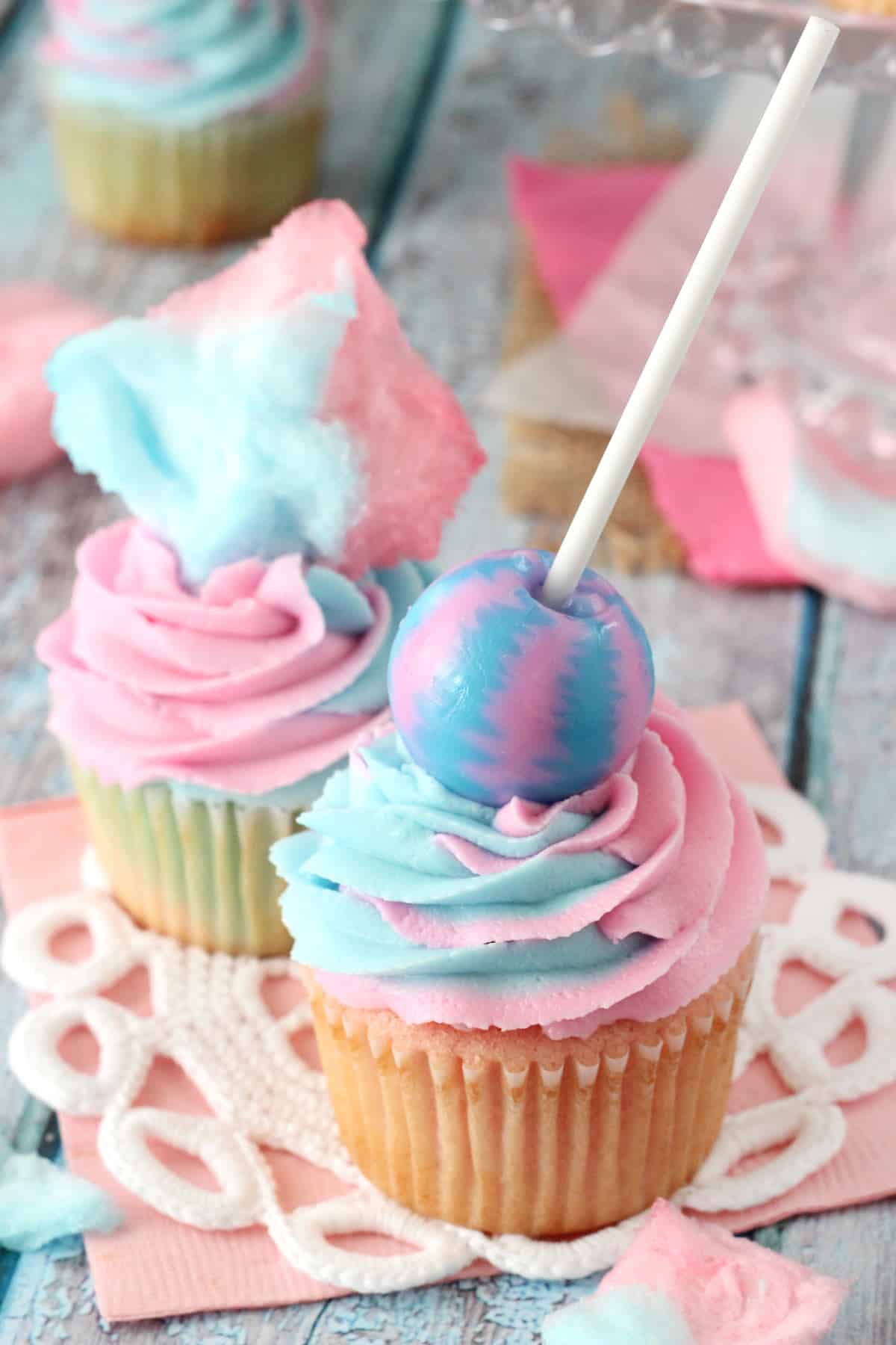 Two cotton candy cupcakes on a doily.