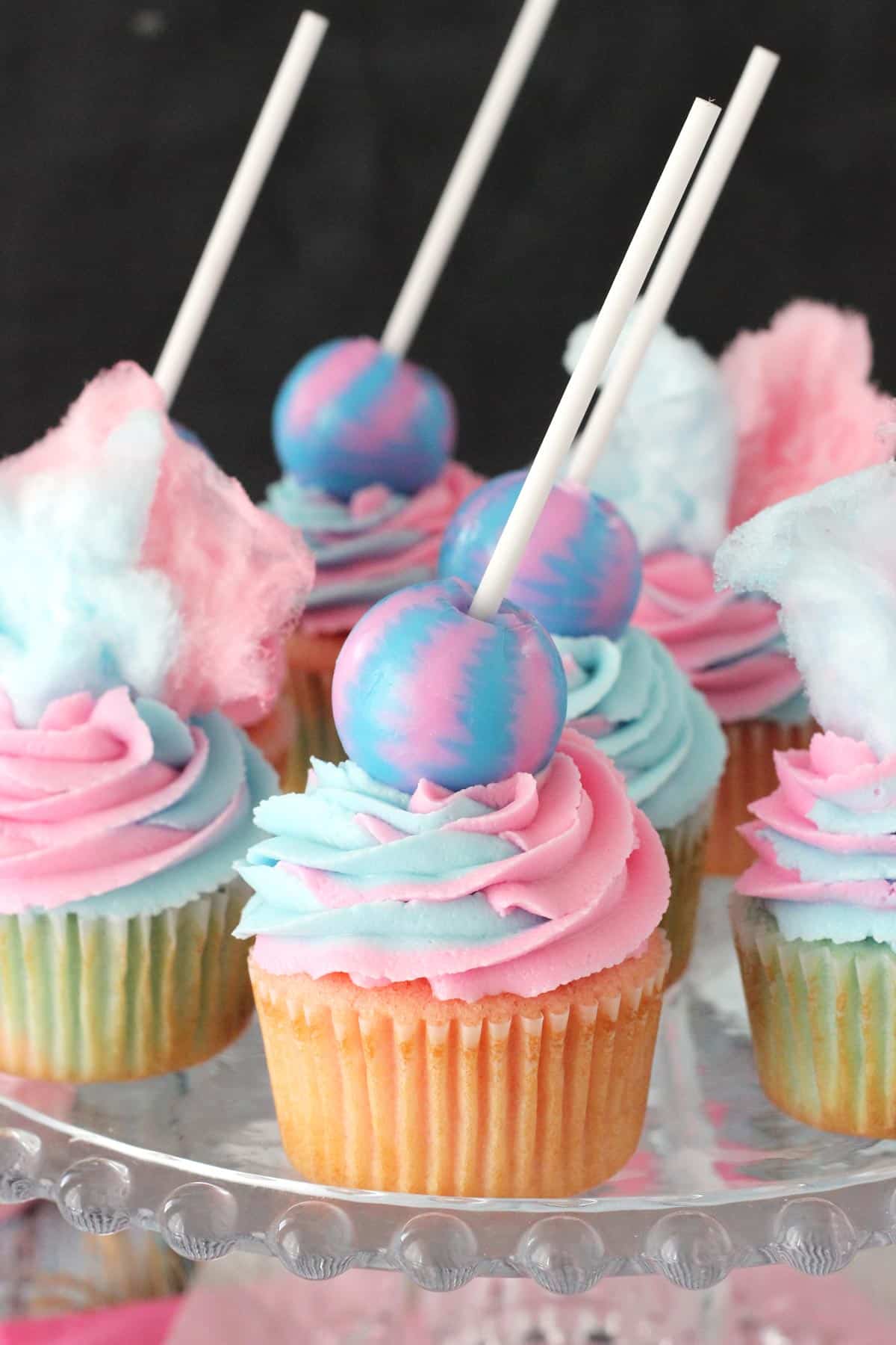 A glass tray covered with cotton candy cupcakes.