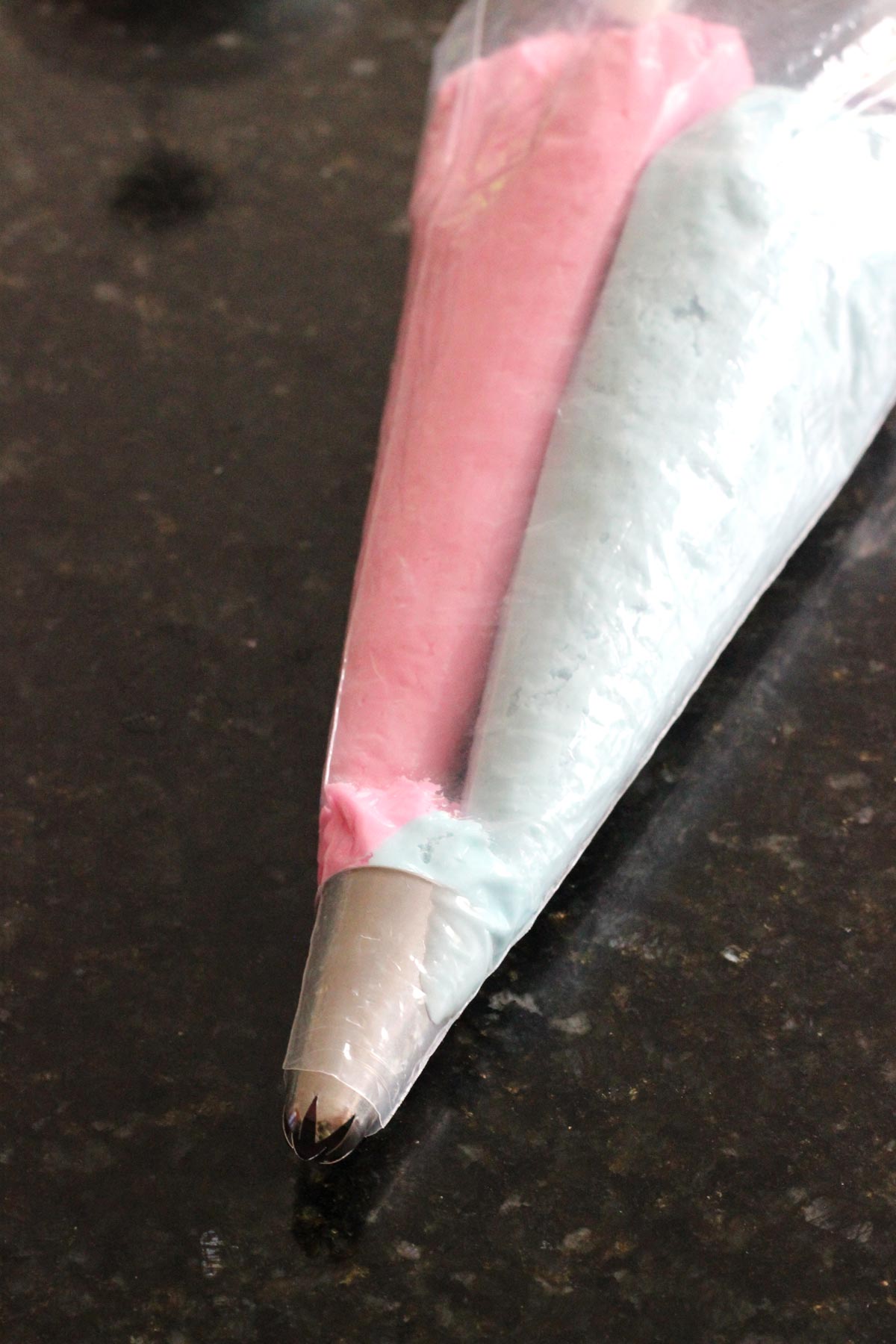 A bag of frosting with pink and blue frosting in it.