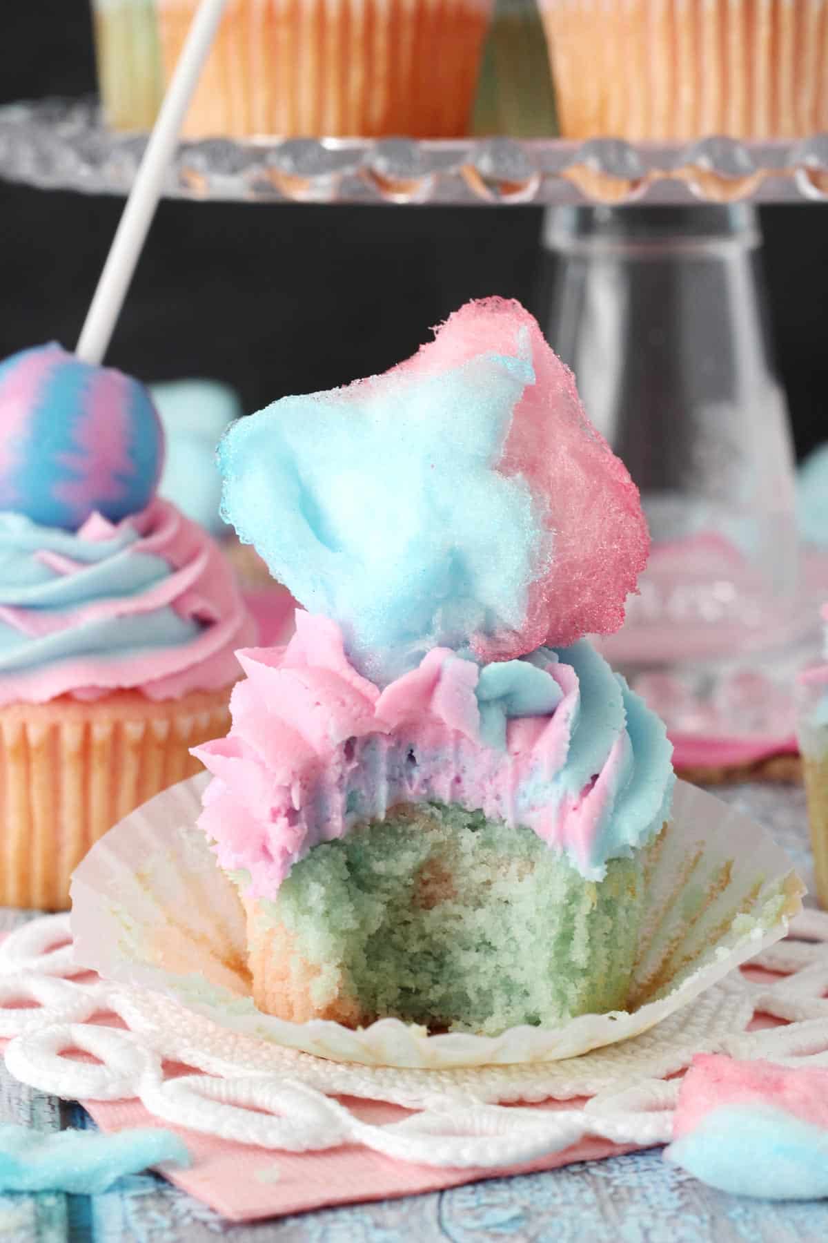 A cotton candy cupcake with a bite taken out of it.