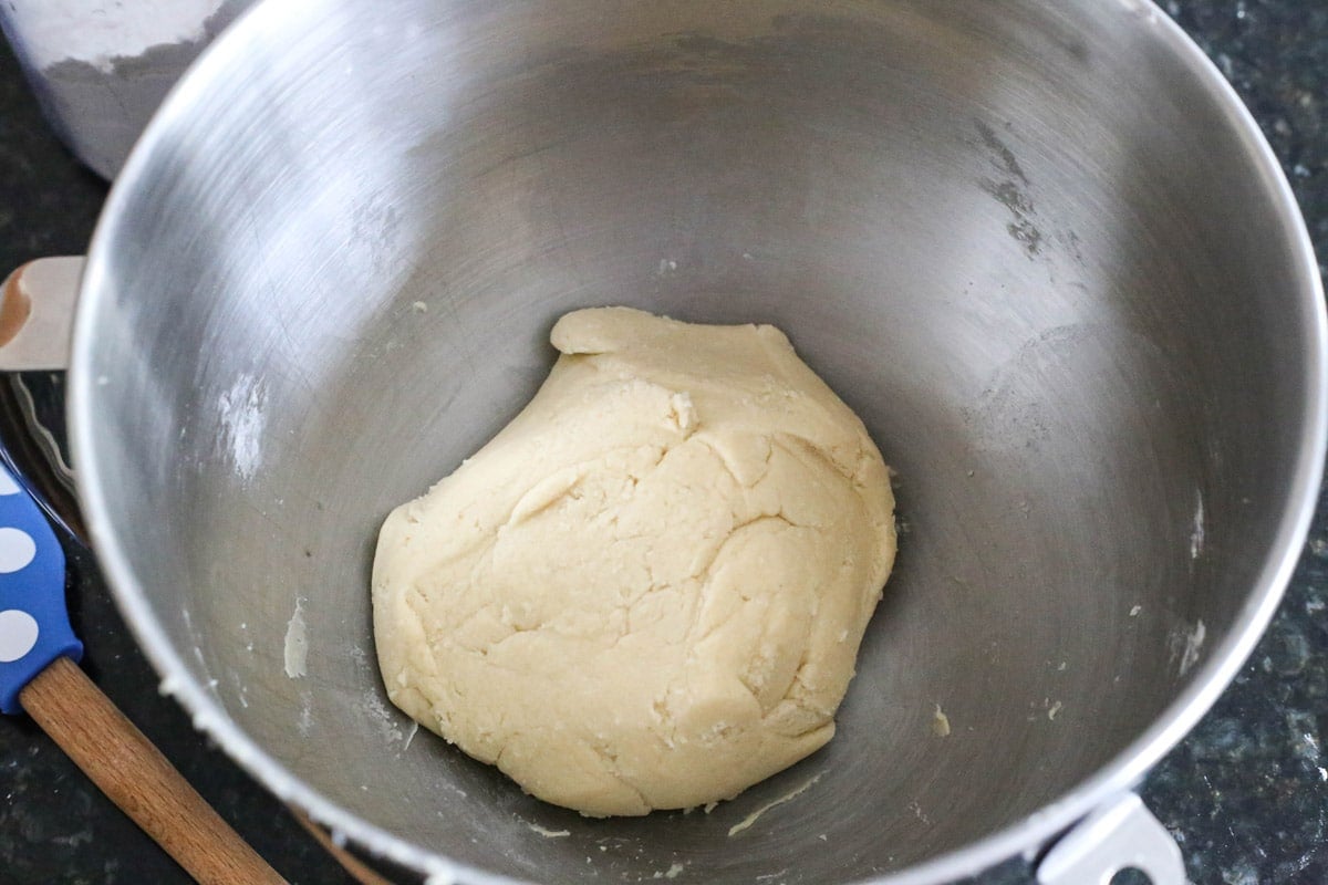 A ball of sugar cookie dough in a mixer bowl.
