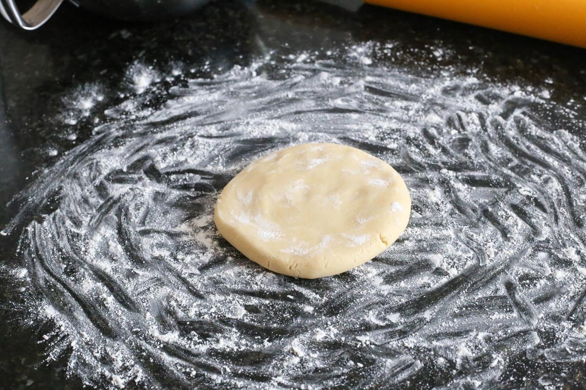 A disc of cutout sugar cookie dough on a floured surface.