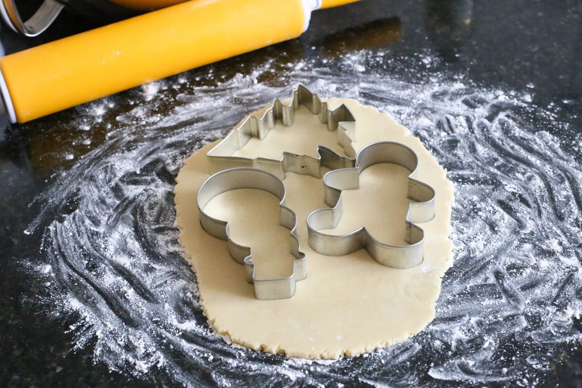 Rolled out sugar cookie dough with cookie cutters inserted.