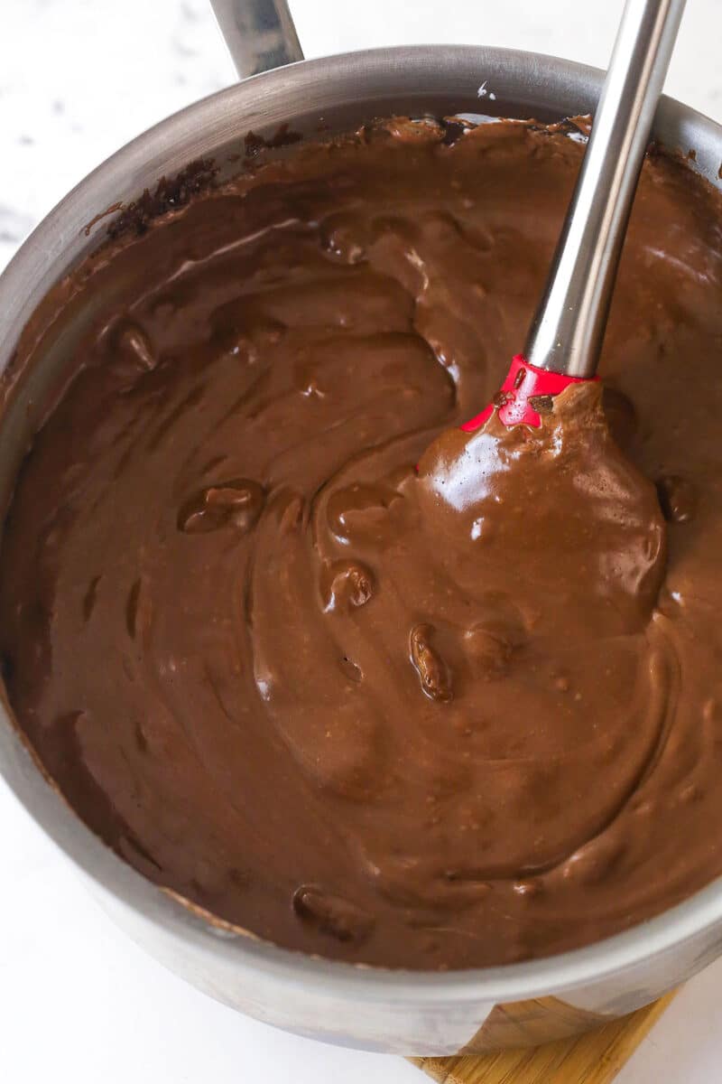 Stirring marshmallow fluff, vanilla, and chopped walnuts into fantasy fudge.