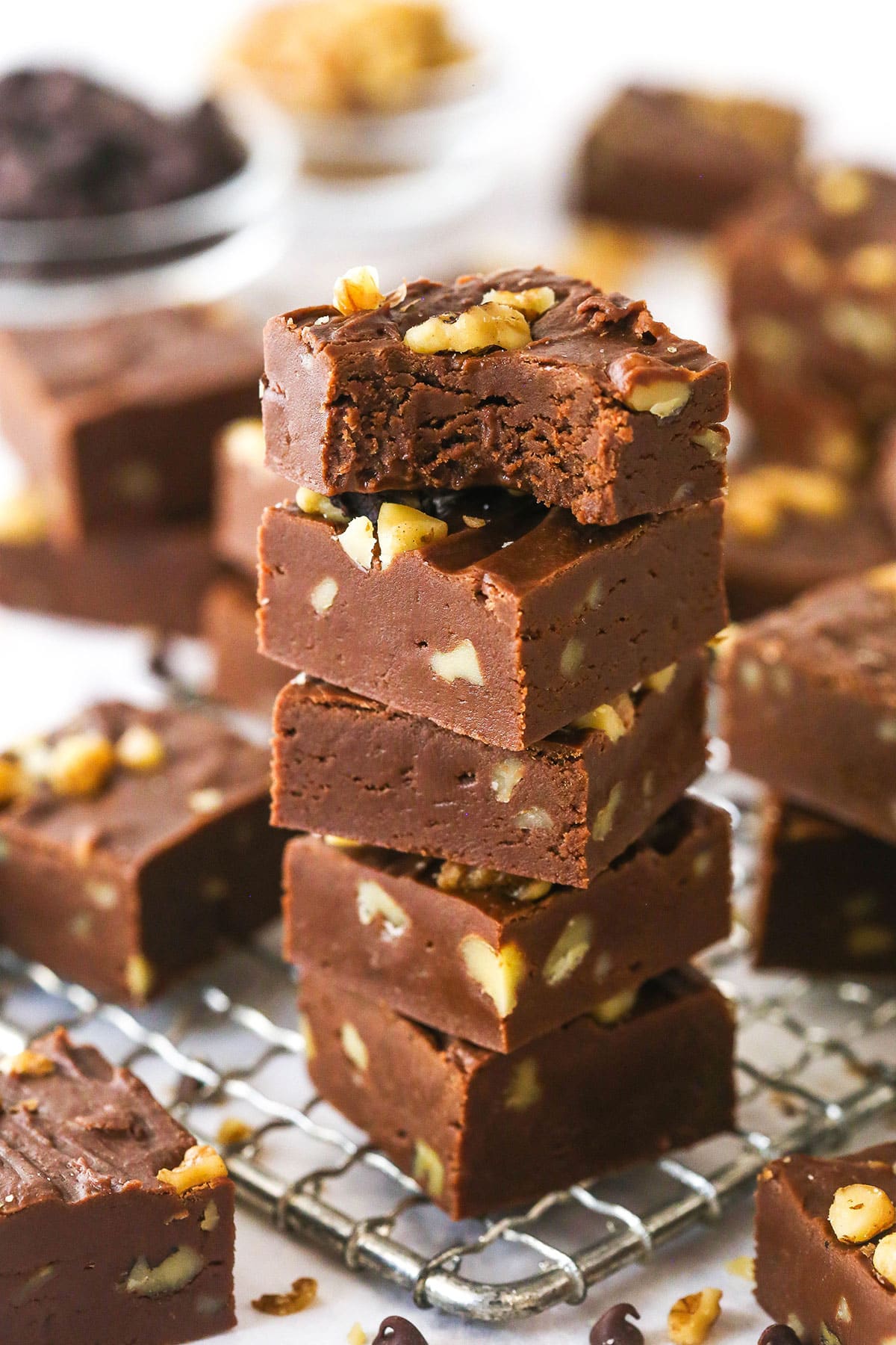 A stack of fantasy fudge on a wire rack. The top piece has a bite taken out of it.