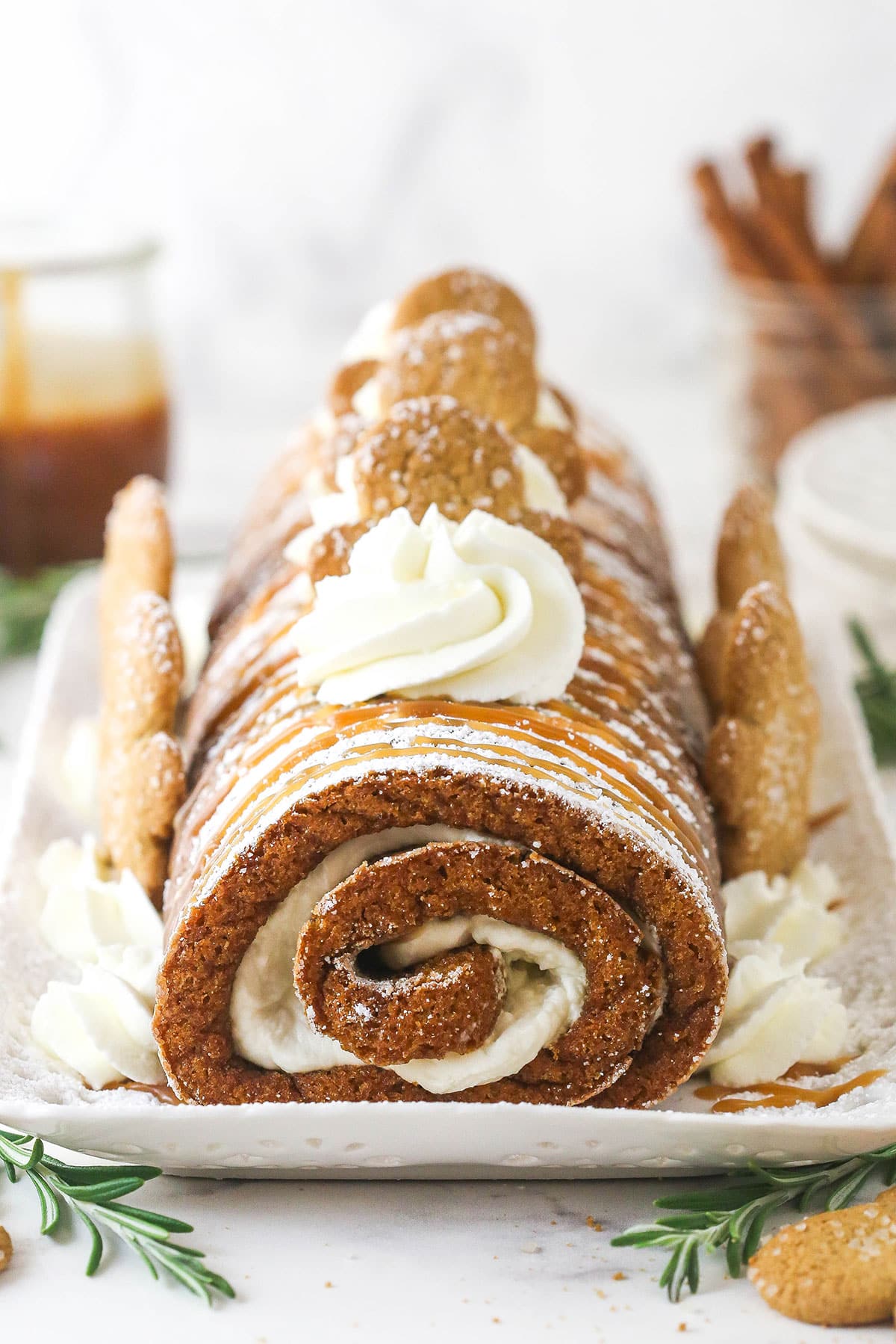 Gingerbread cake roll is a fun alternative to the classic, featuring a moist, spiced cake wrapped around a caramel and cream cheese filling. Gingerbread cake roll decorated with cream cheese whipped cream and gingerbread men.