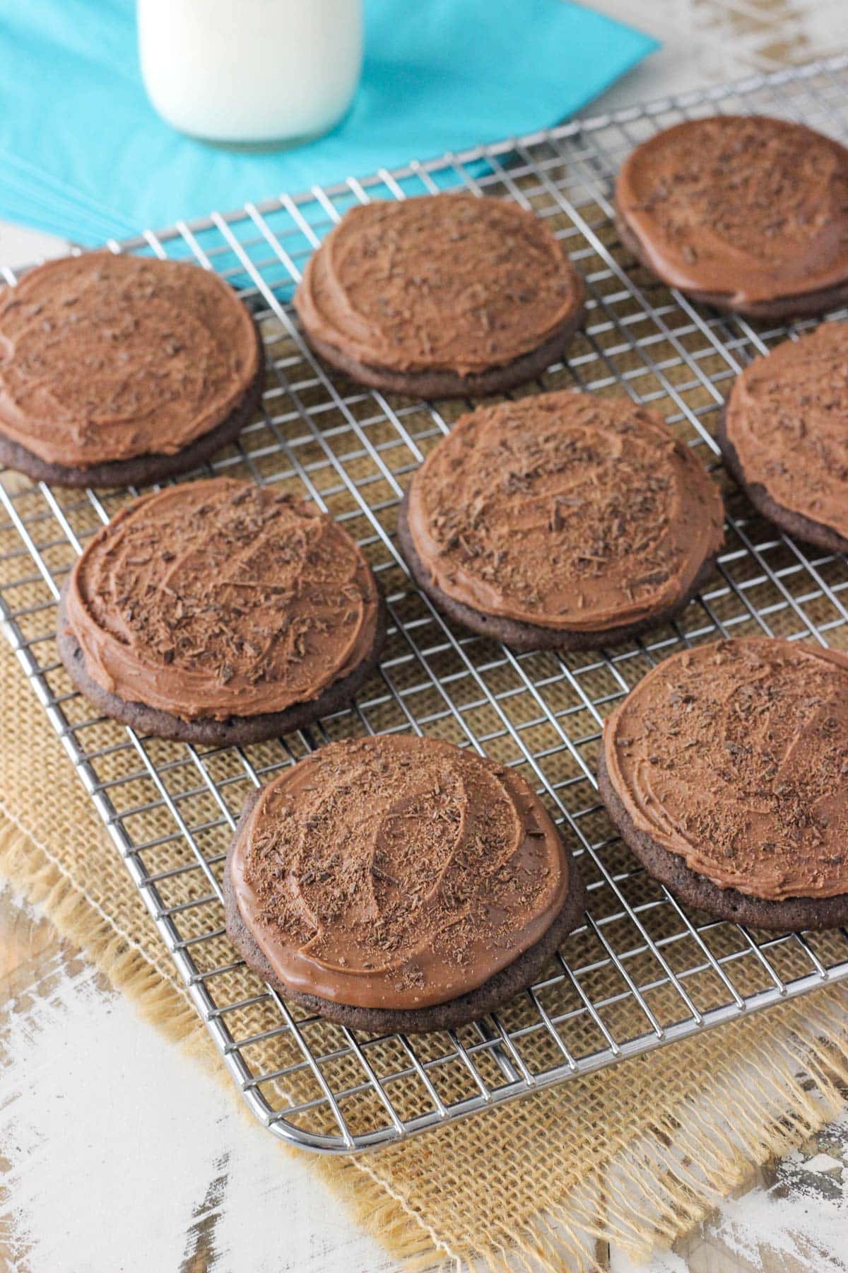 Side view of iced chocolate cookies on a wire rack.