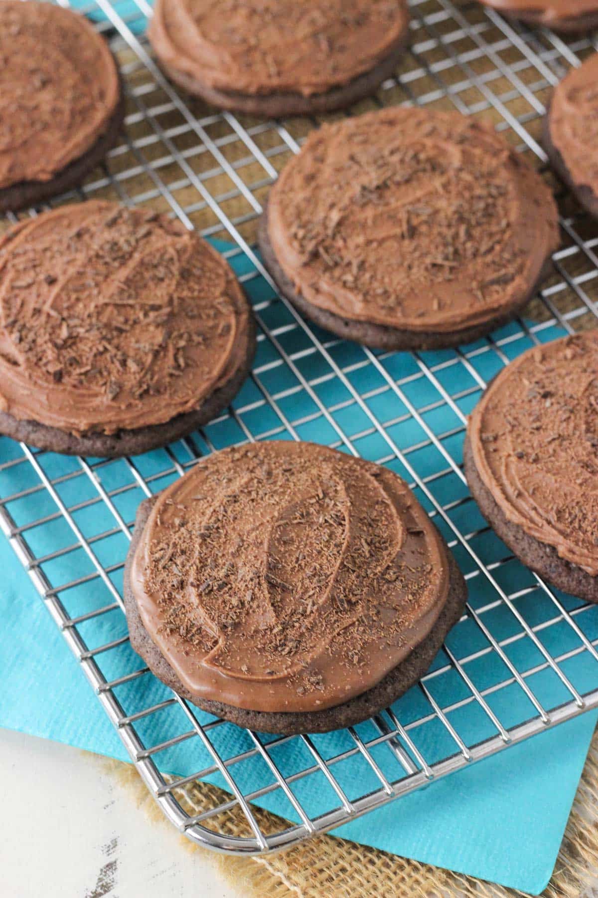 A metal rack topped with iced chocolate cookies.