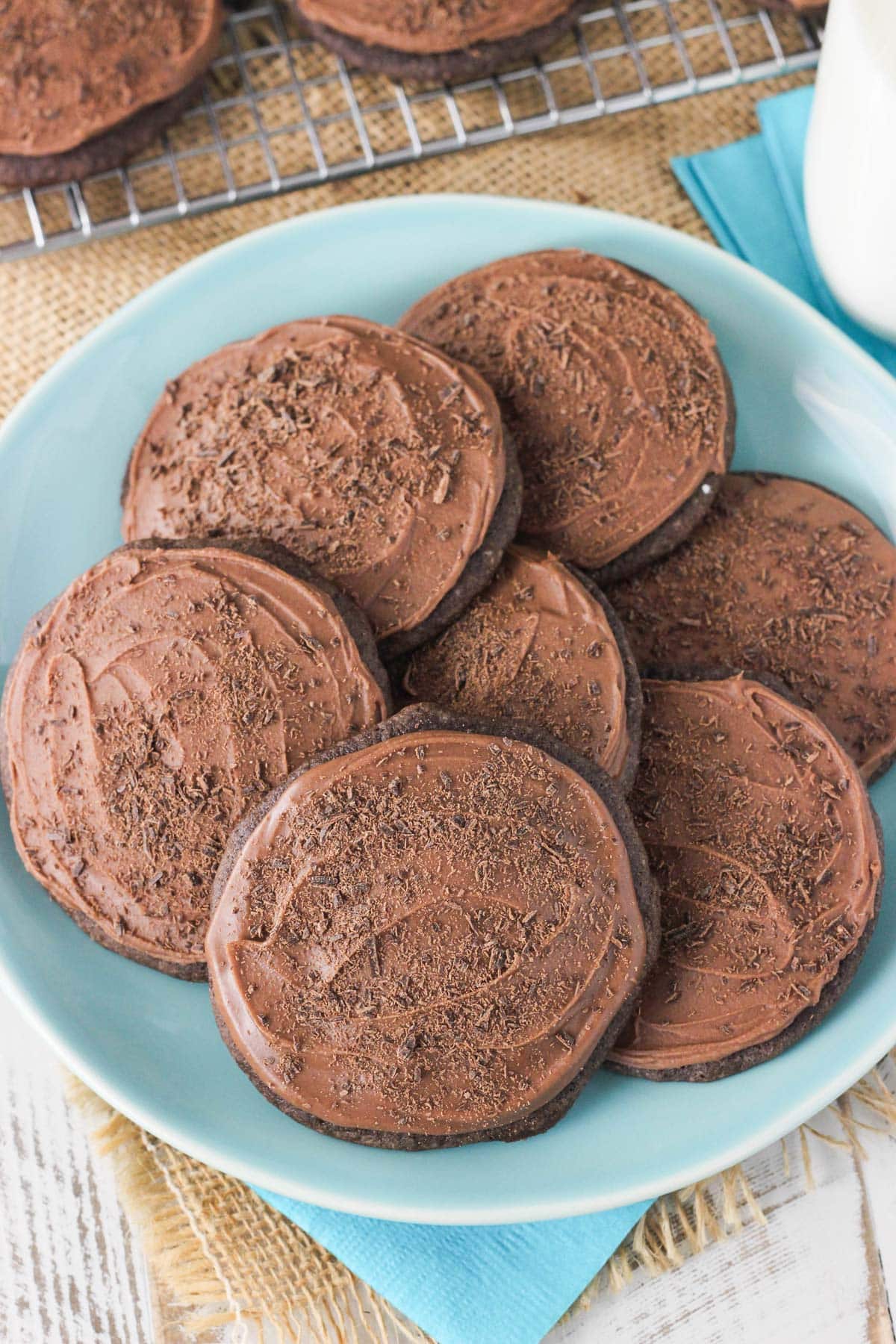 A blue plate with iced chocolate cookies on it.
