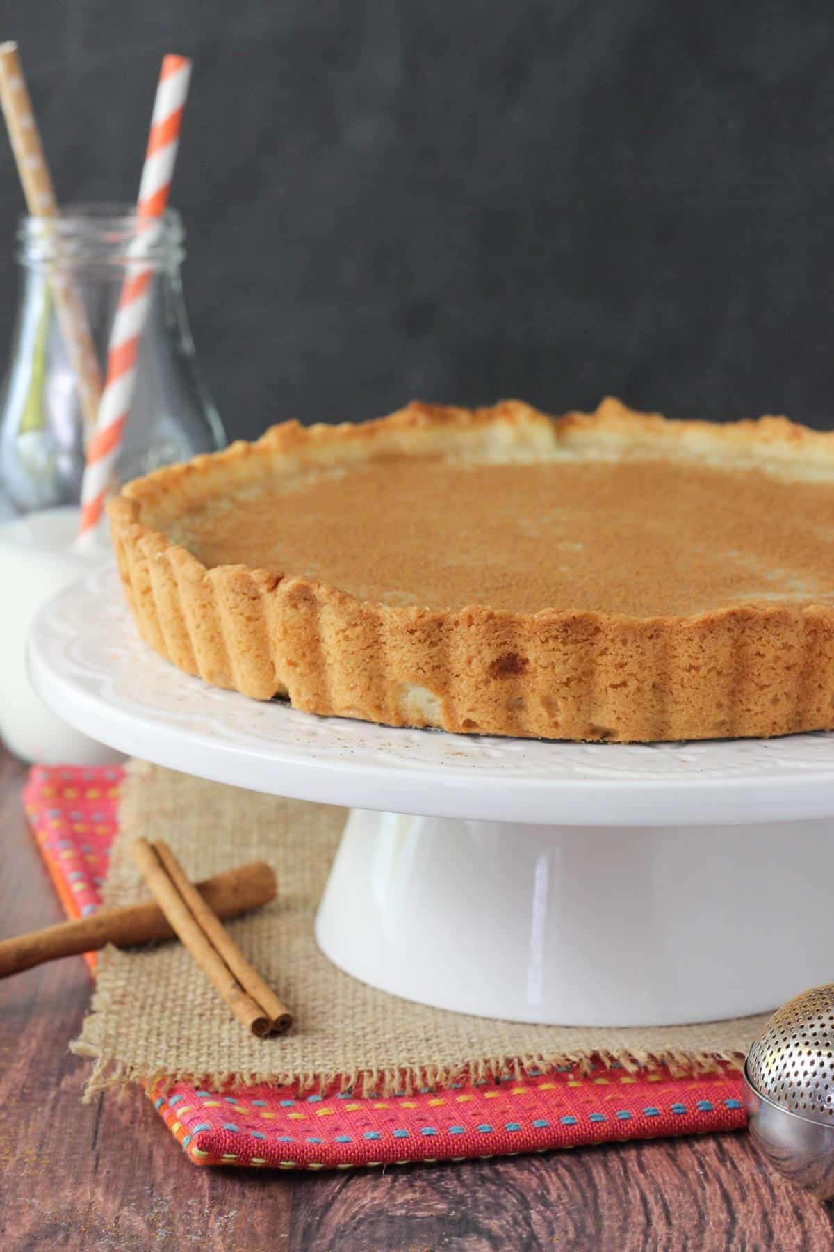 Side view of a milk tart on a white cake stand.