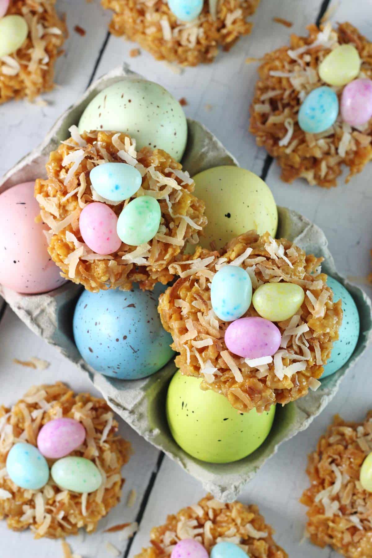 No Bake Coconut Caramel Nest Cookies Two no bake caramel coconut nest cookies on top of a carton of colorful eggs.