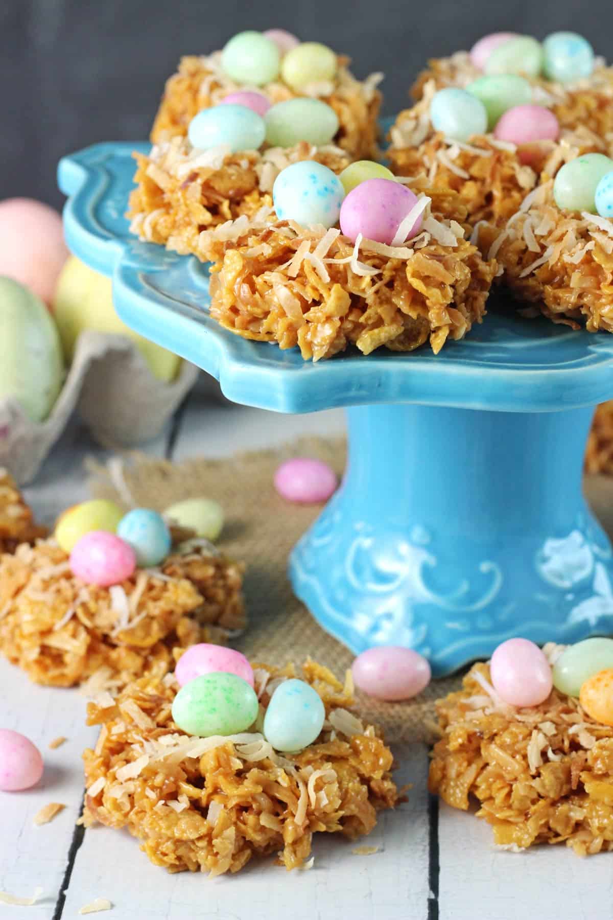 No Bake Coconut Caramel Nest Cookies A blue cake stand surrounded and topped with no bake caramel coconut nest cookies.