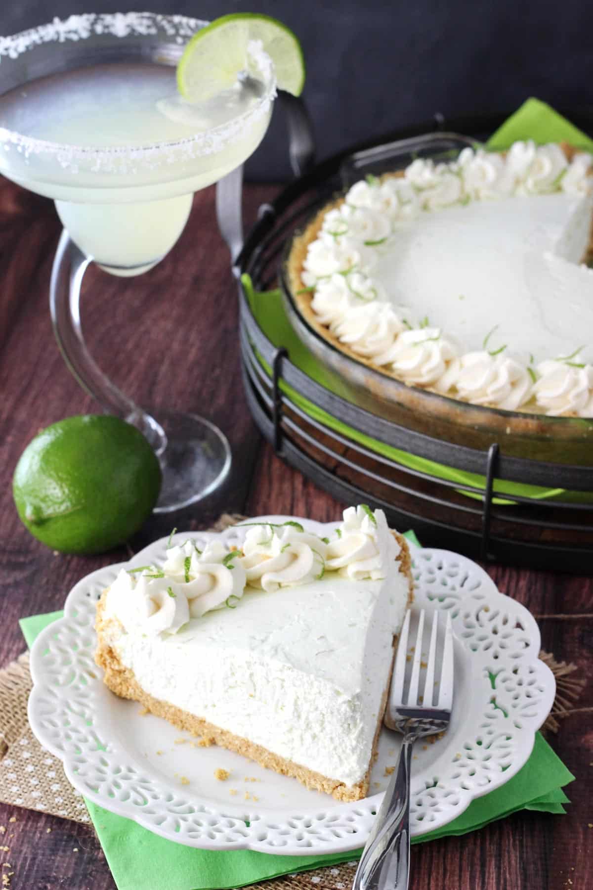 A slice of no bake margarita pie with the rest of the pie in the background.