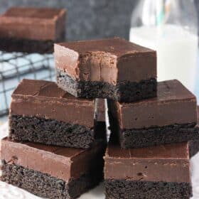 Stacked Nutella fudge brownies on a white plate with a bite taken out of top brownie.