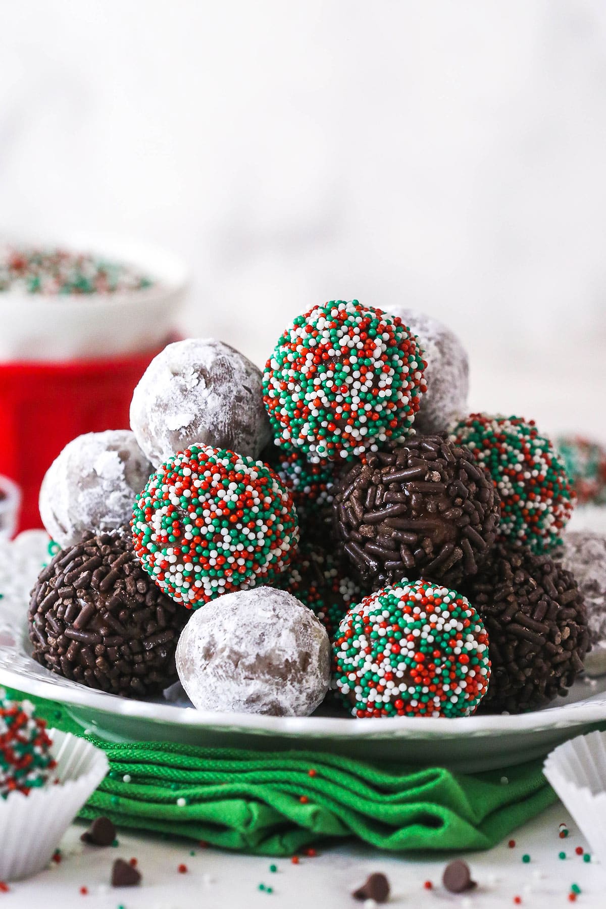 These customizable no-bake rum balls are a holiday must-have, perfect for gifting, gatherings, or adding to your festive cookie tray! A pile of holiday rum balls on a plate.