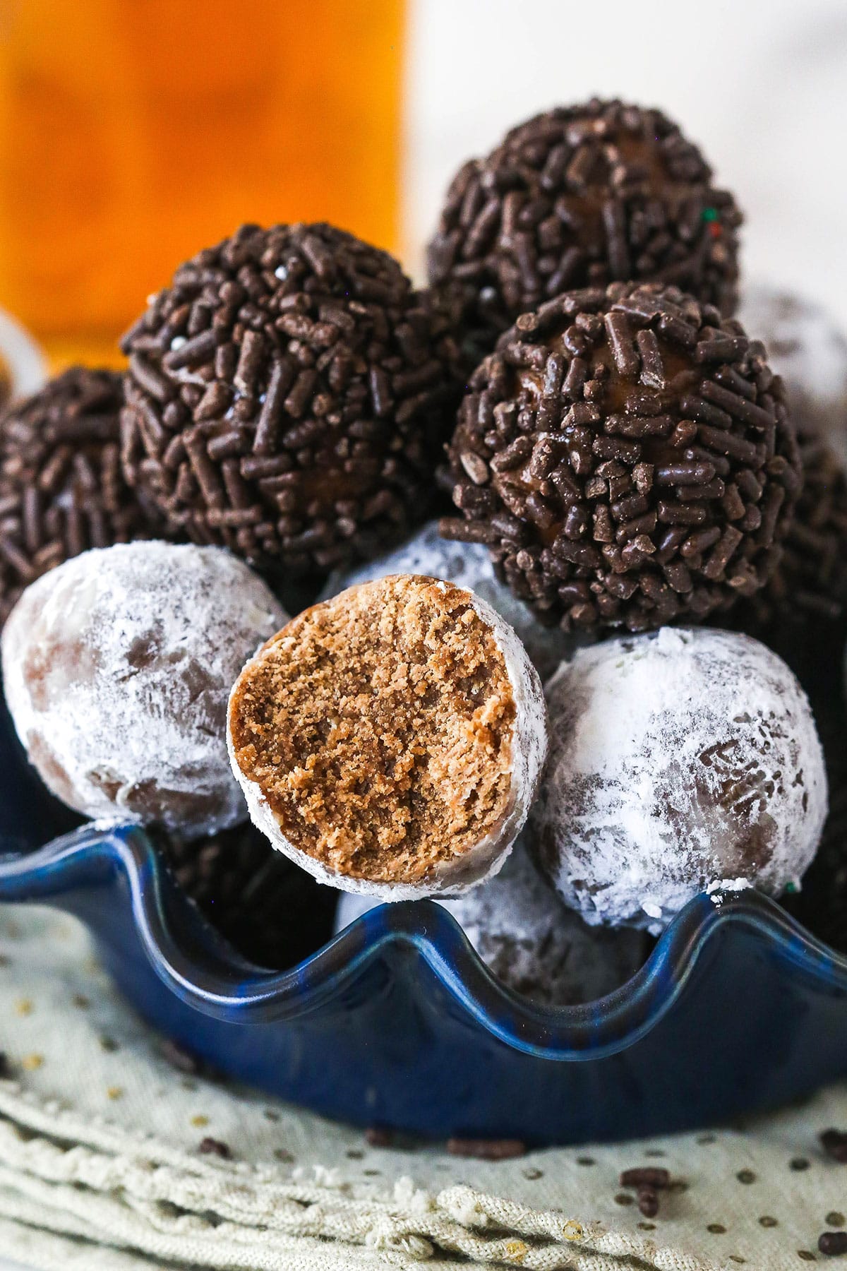 These customizable no-bake rum balls are a holiday must-have, perfect for gifting, gatherings, or adding to your festive cookie tray! Rum balls in a bowl. One has a bite taken out of it.