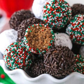 Rum balls in a bowl. One has a bite taken out of it to reveal the center.