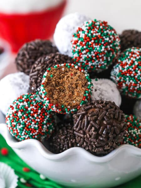 Rum balls in a bowl. One has a bite taken out of it to reveal the center.