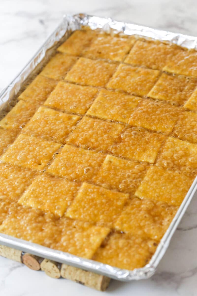 This saltine cracker toffee is rich, buttery, and full of crispy crackers. With a chocolate topping and crunchy pecans, it's a holiday must! Baked, toffee-soaked saltine crackers on a cookie sheet.