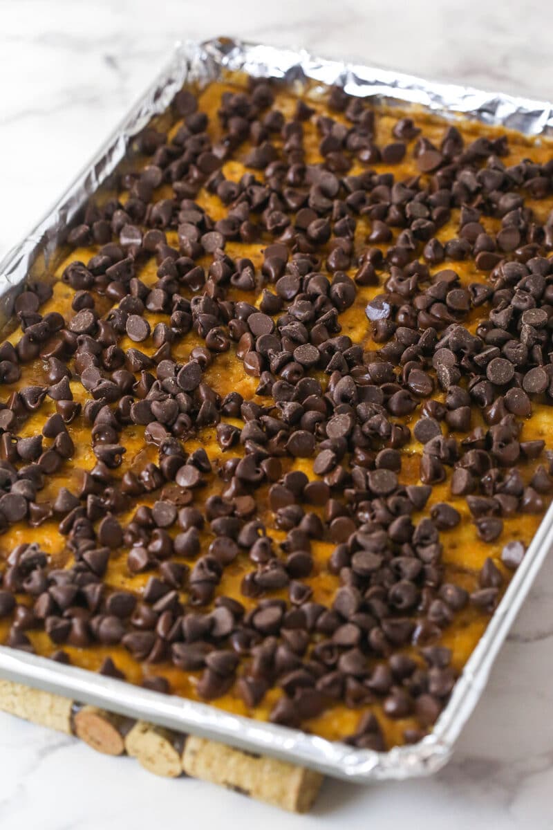 This saltine cracker toffee is rich, buttery, and full of crispy crackers. With a chocolate topping and crunchy pecans, it's a holiday must! Chocolate chips scattered over hot saltine cracker toffee.