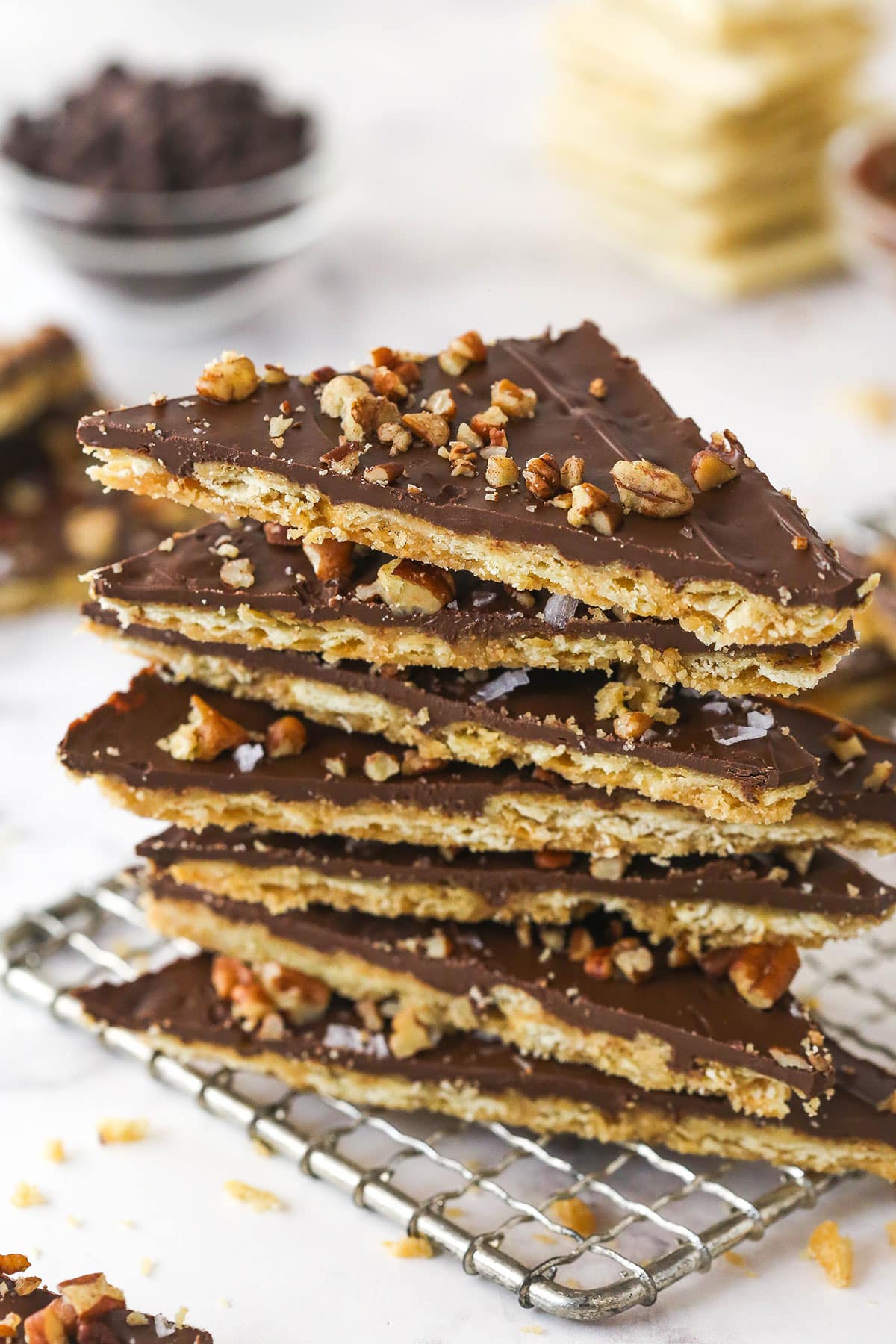 This saltine cracker toffee is rich, buttery, and full of crispy crackers. With a chocolate topping and crunchy pecans, it's a holiday must! Saltine cracker toffee pieces stacked on a cooling rack.
