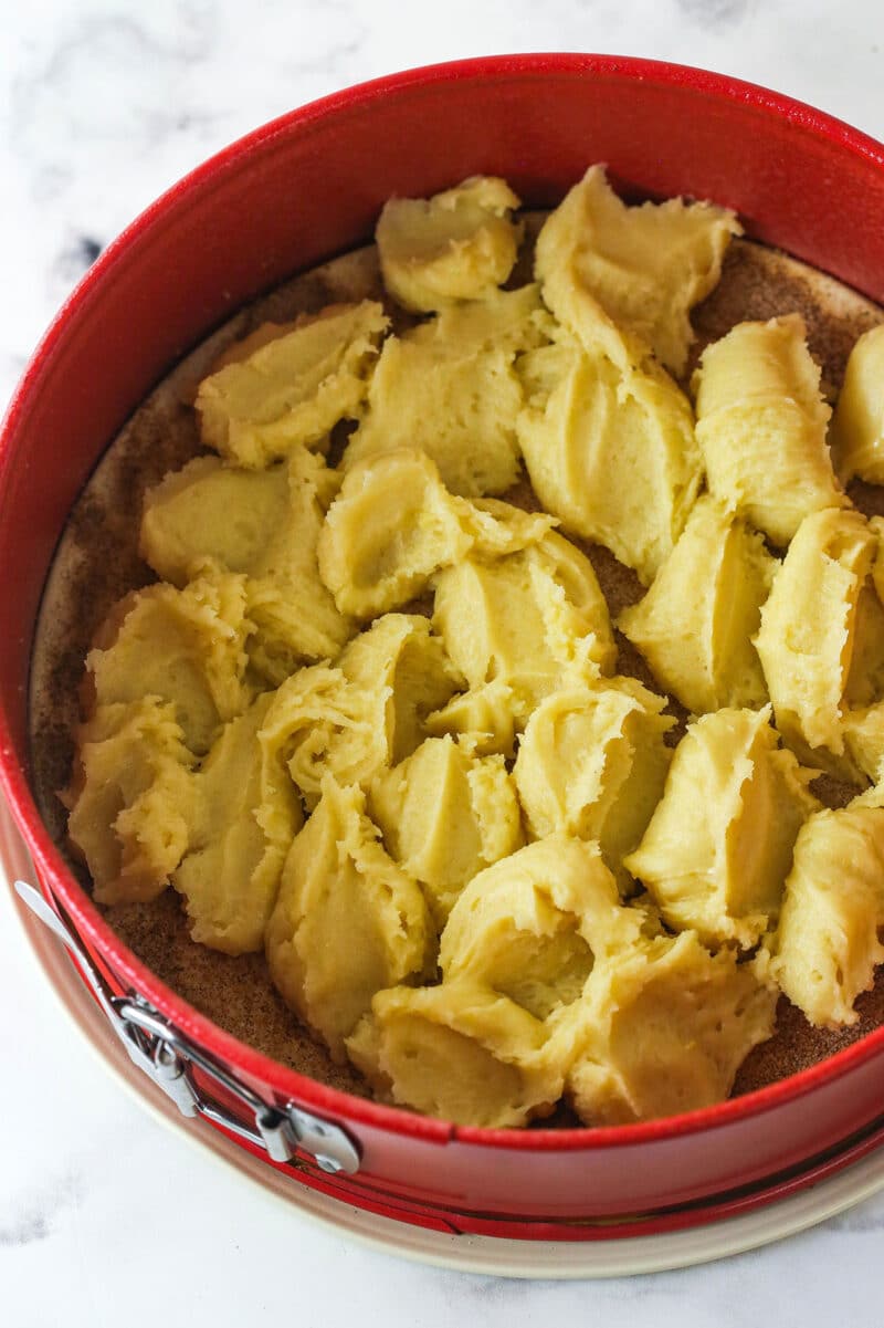 Dollops of snickerdoodle dough in the bottom of a springform pan.
