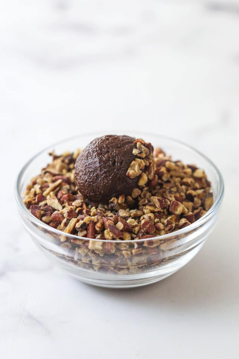 These decadent turtle thumbprint cookies feature a rich chocolate base, gooey caramel center, and crunchy pecan coating. Wow! Rolling a chocolate cookie dough ball in chopped pecans.