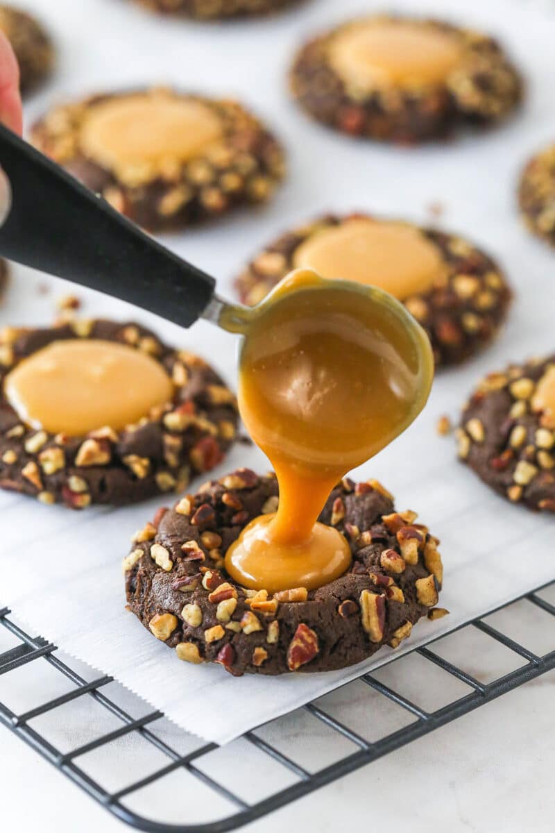 These decadent turtle thumbprint cookies feature a rich chocolate base, gooey caramel center, and crunchy pecan coating. Wow! Filling pecan-crusted cookies with caramel sauce.