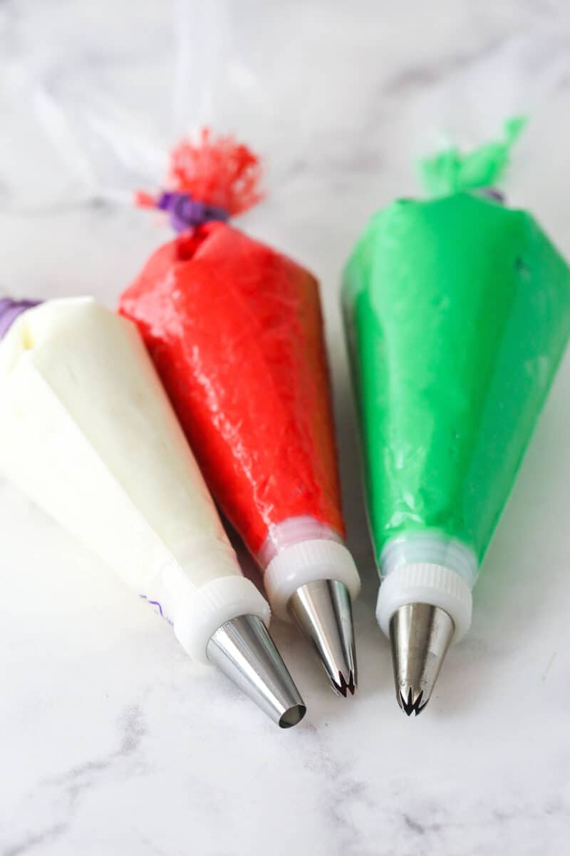 colored buttercream in three piping bags with piping tips