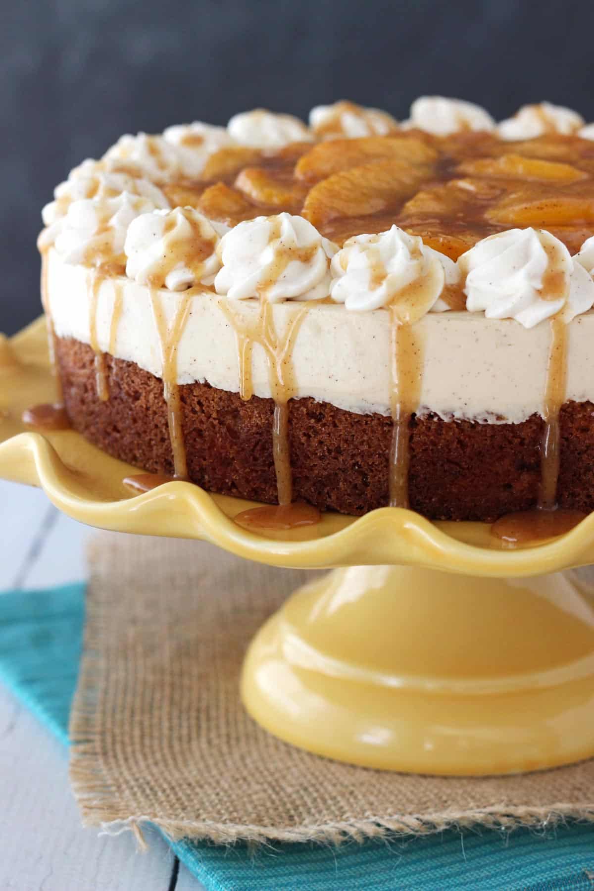 Close up of the side of a peach caramel blondie cheesecake on a yellow cake stand.