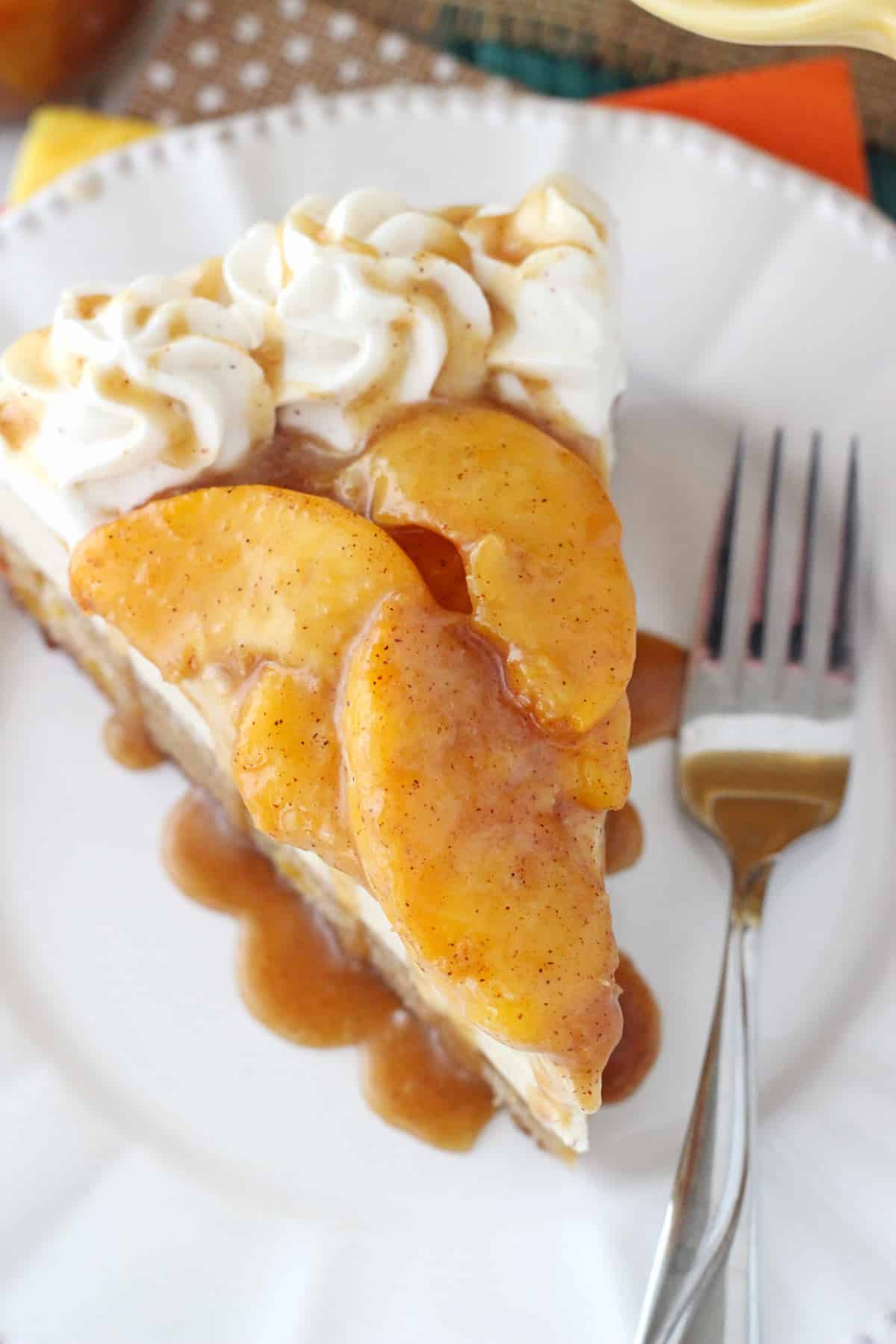 Top view of a slice of peach caramel blondie cheesecake on a white plate next to a fork.