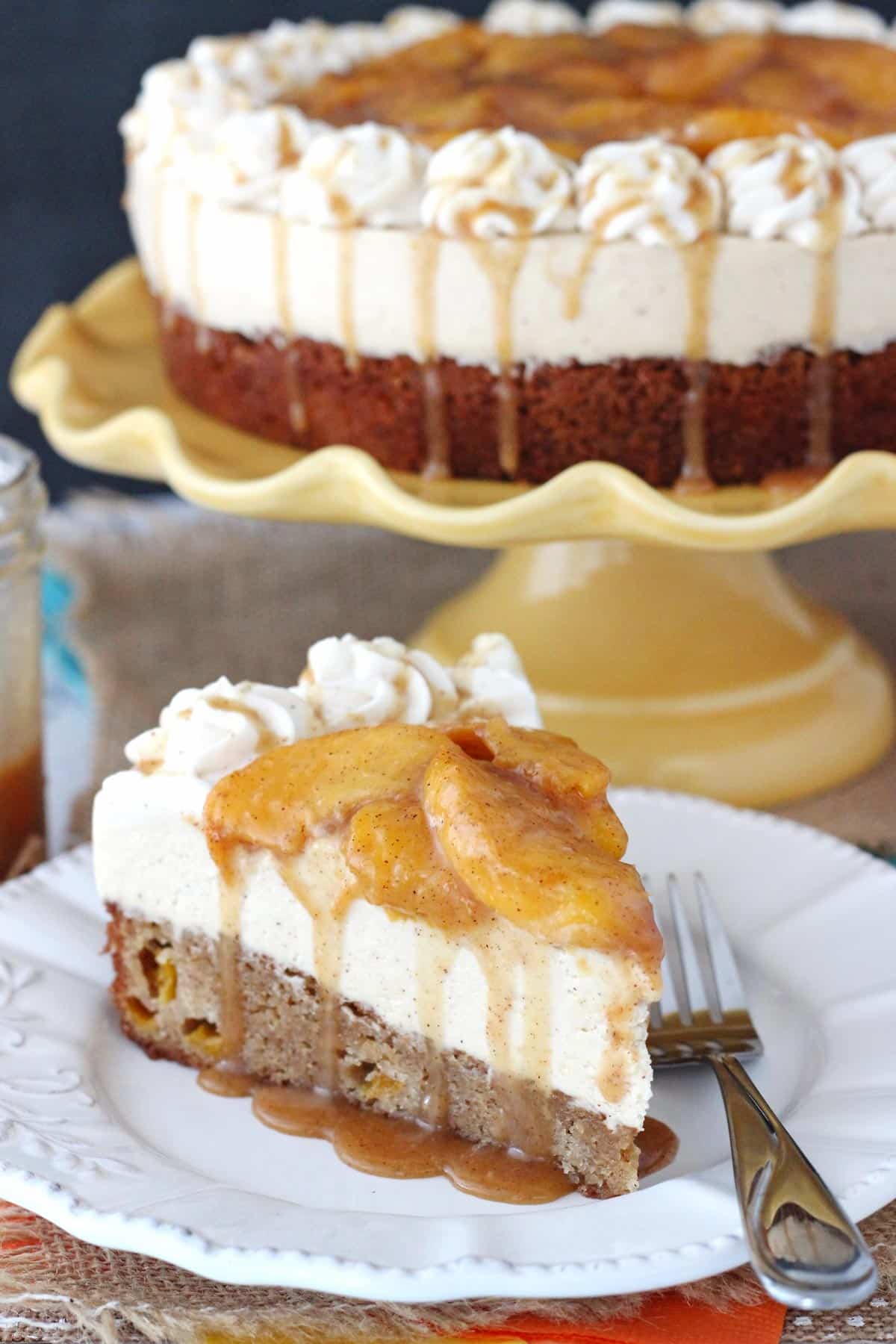 Side view of a slice of peach caramel blondie cheesecake on a white plate with the rest of the cheesecake in the background.
