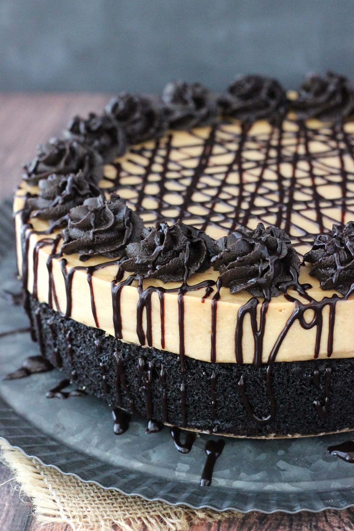 Close up of the side of a peanut butter truffle chocolate cake on a silver plate.