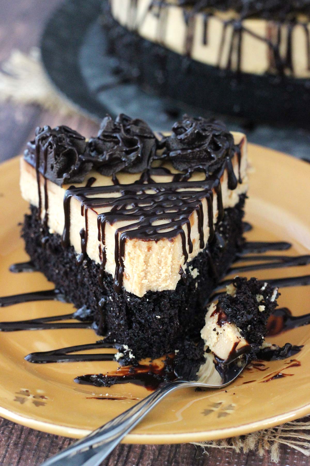 A slice of peanut butter truffle chocolate cake with a bite removed on a fork on a gold plate.