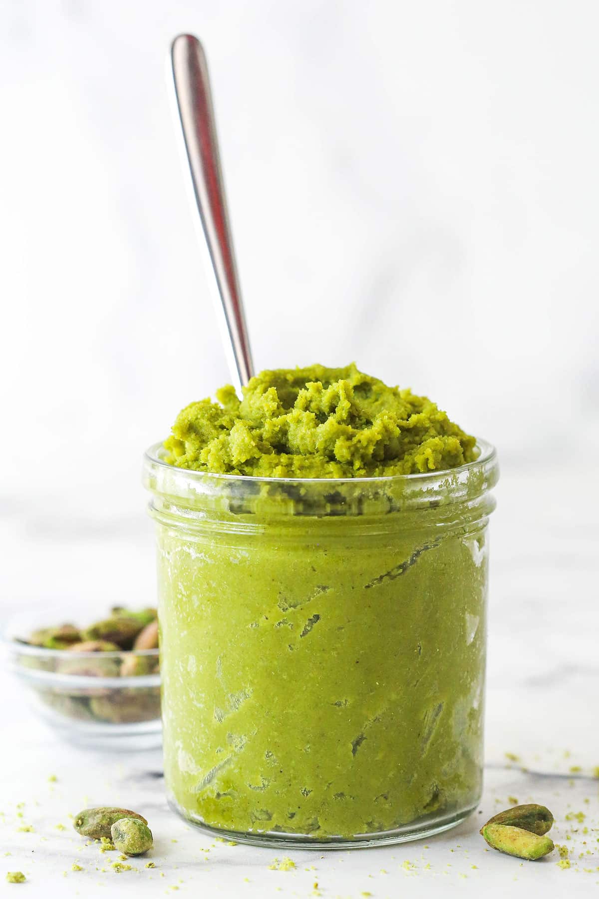 A jar of pistachio paste with a spoon in it