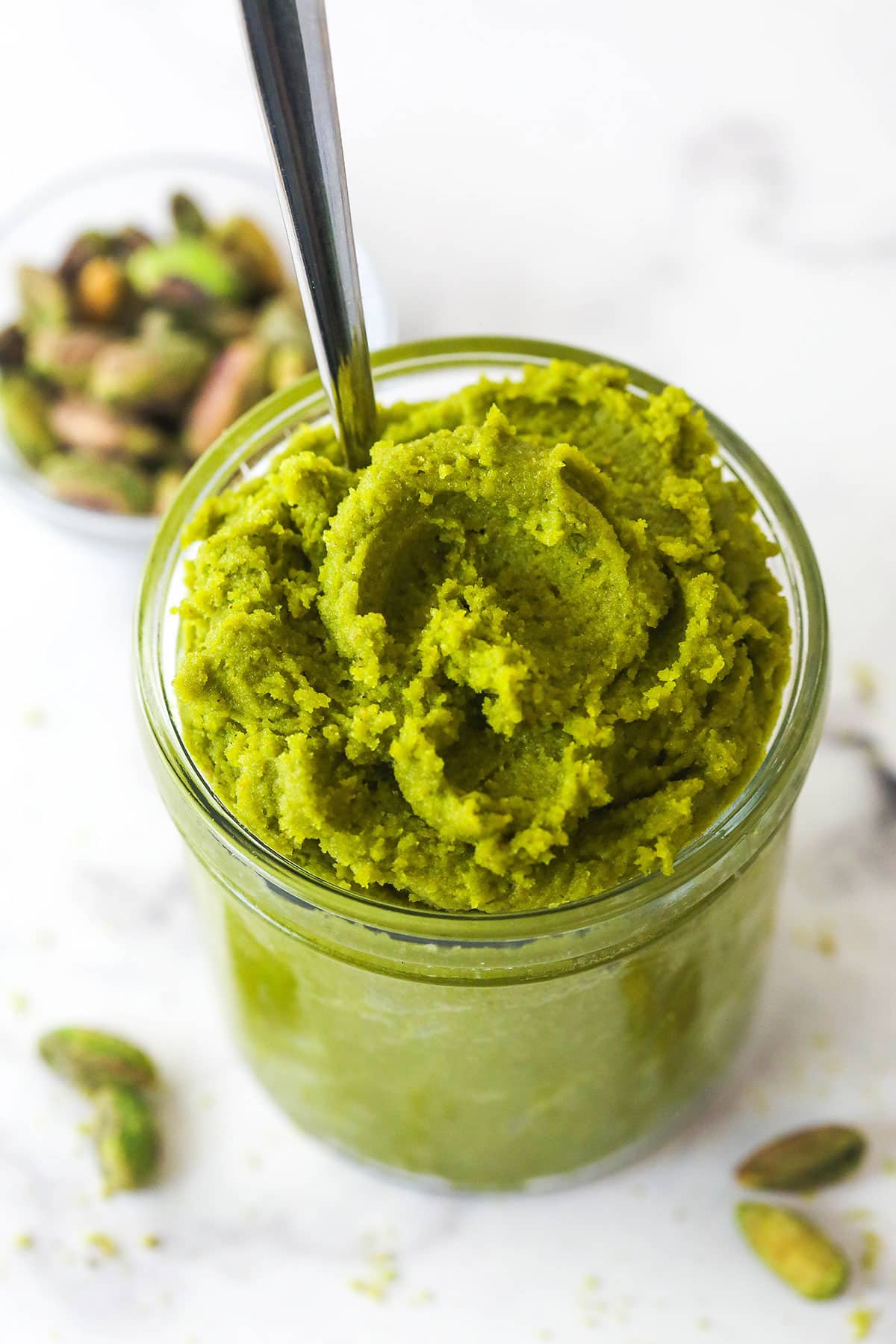 Overhead view of a jar of pistachio paste with a spoon