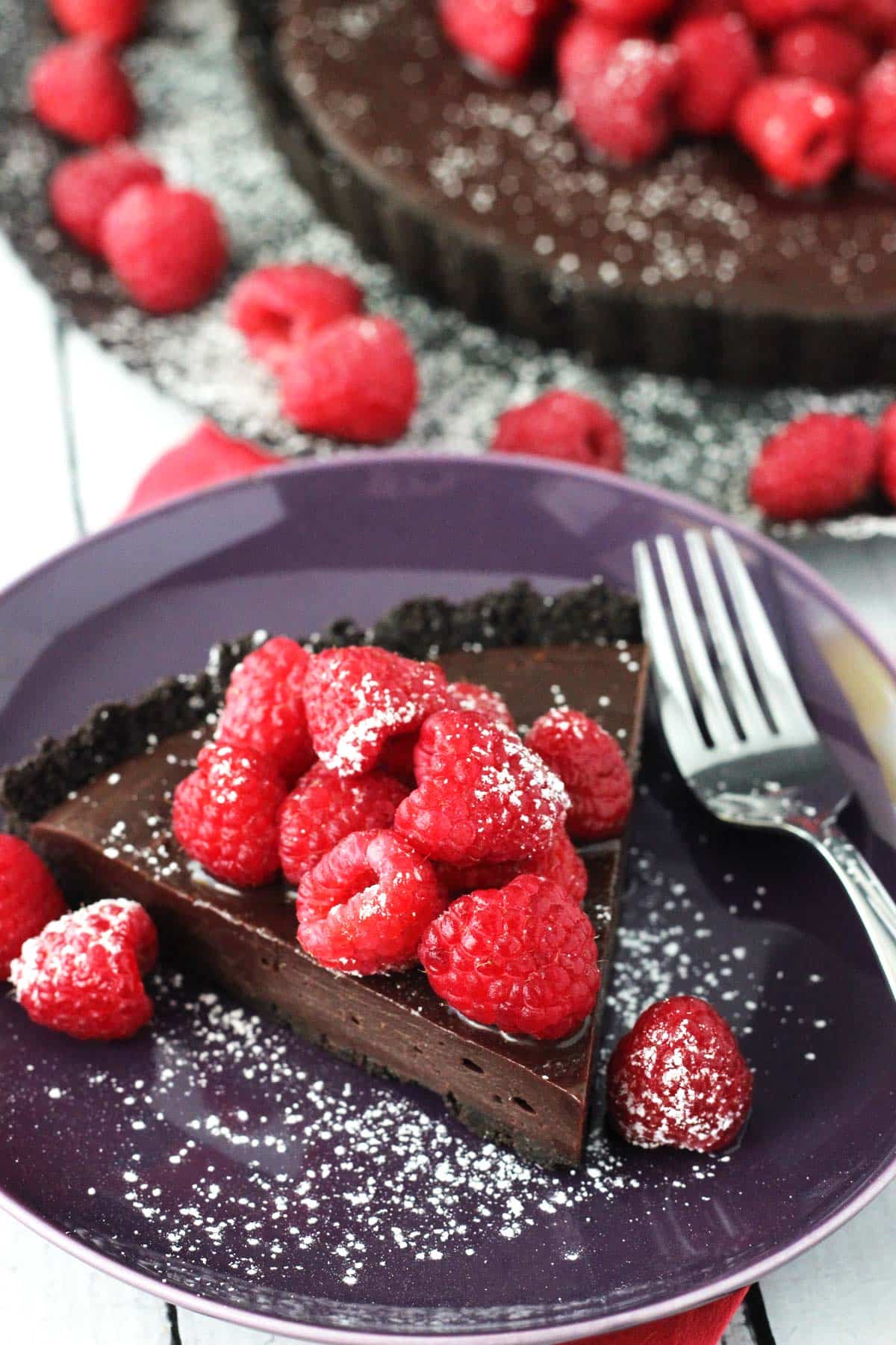 A slice of raspberry nutella tart on a purple plate.