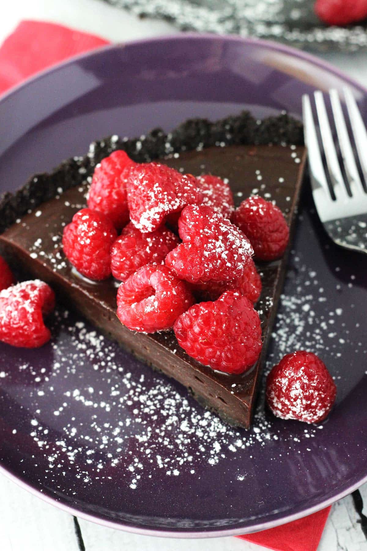A slice of raspberry nutella tart on a purple plate.
